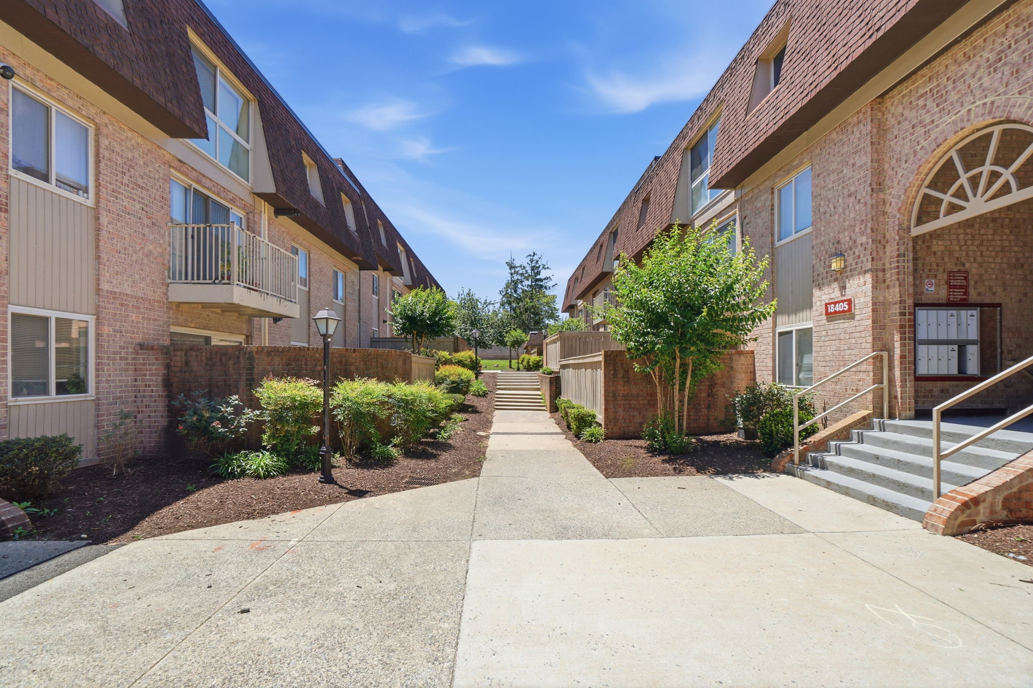 A sunny day at a brick apartment complex with a clear blue sky.